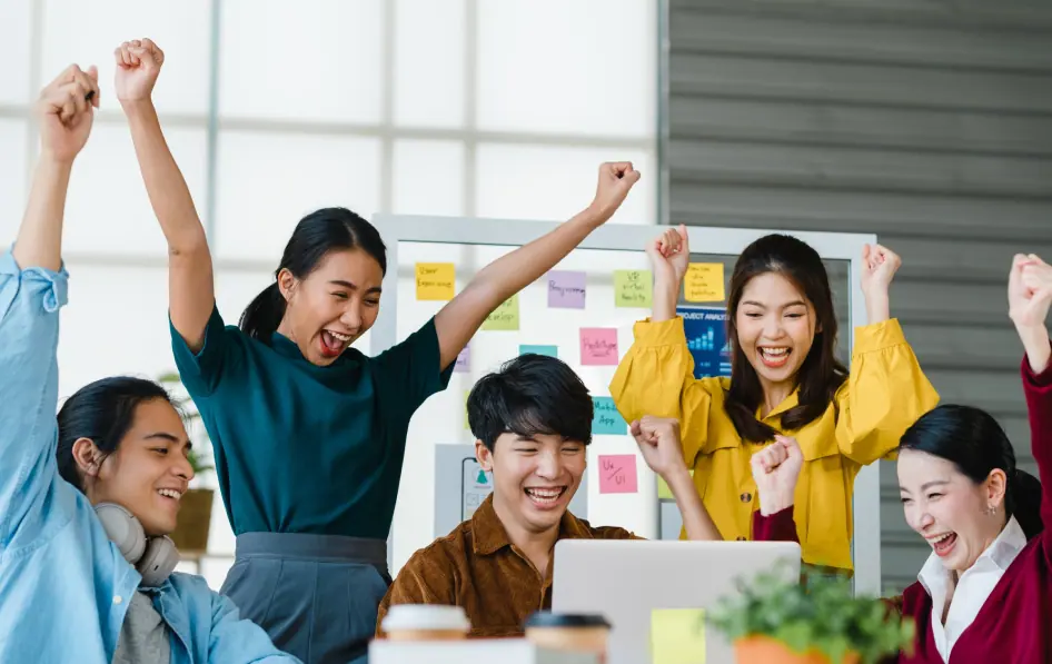 A team celebrating with raised arms in a bright workspace