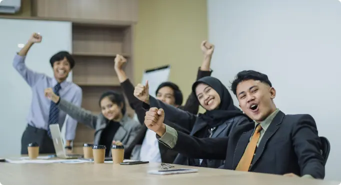 Colleagues cheering together around a meeting table